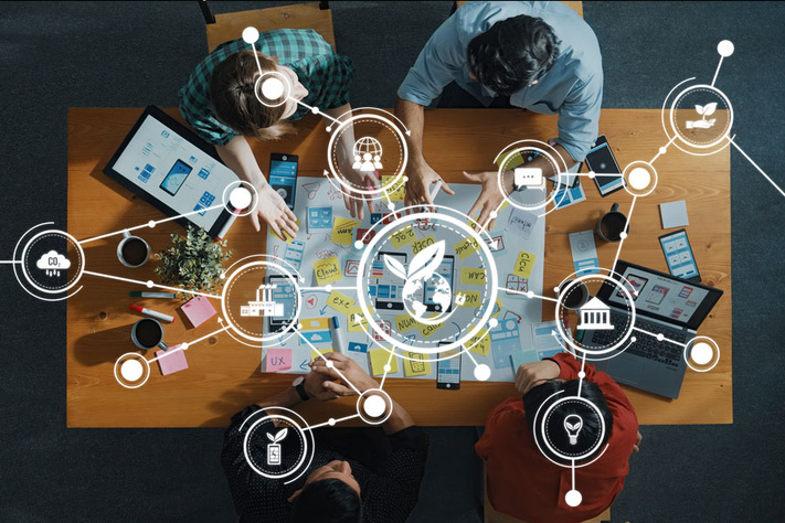 A top view of a diverse team engaged in collaborative business planning, highlighting green strategies and innovative digital solutions at a modern workspace.